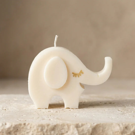White elephant-shaped candle on a beige surface with a neutral background