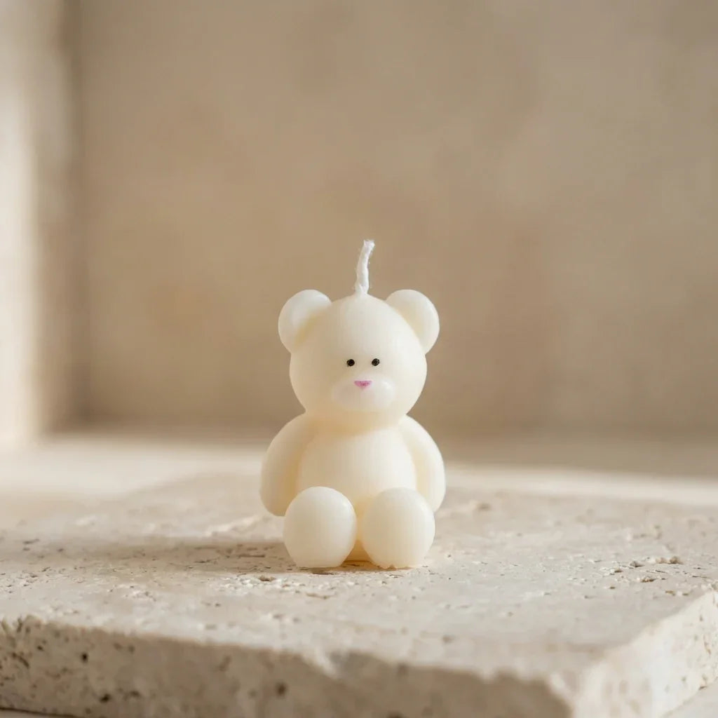 A tiny, chubby unscented teddy bear candle sitting on a desk, used as aesthetic room decor and a perfect baby shower favor.