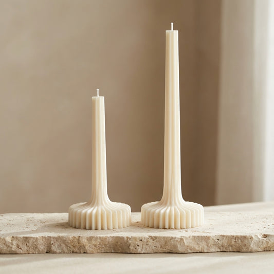 Set of two architectural fluted column candles styled as a minimalist centerpiece on a dining table.