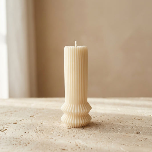Close-up of a hand-poured soy wax architectural fluted pillar candle featuring a ribbed upper column and geometric pedestal base.