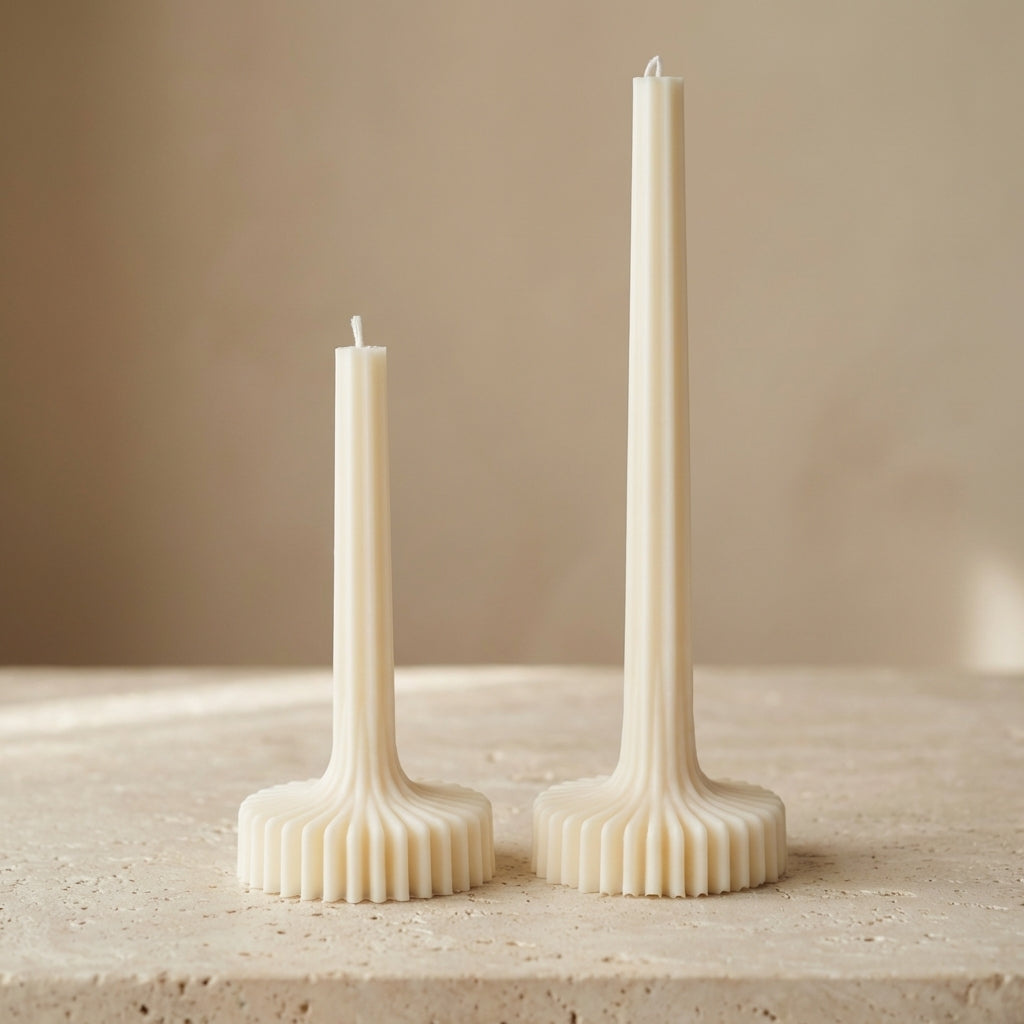 Two white candles in decorative holders on a beige surface with a neutral background