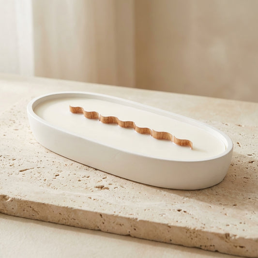 Close-up of a handcrafted artisan oval centerpiece candle highlighting its continuous wavy natural wood wick and smooth gypsum vessel.