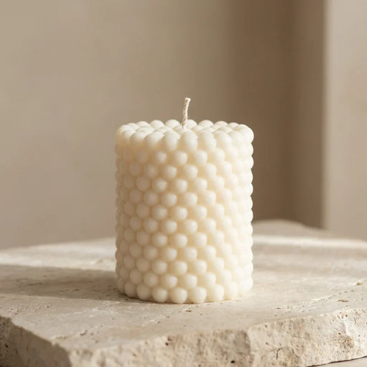 Close-up of a hand-poured soy wax beaded pillar candle highlighting its unique all-over bubble texture.