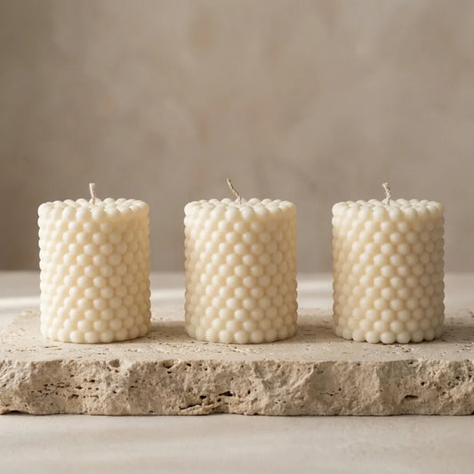 Close-up of a three hand-poured soy wax beaded pillar candles highlighting its unique all-over bubble texture.