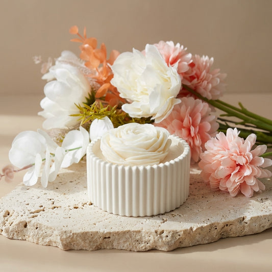 Close-up of a handcrafted ribbed gypsum vessel featuring a breathtaking, hyper-realistic hand-poured wax rose in full bloom.