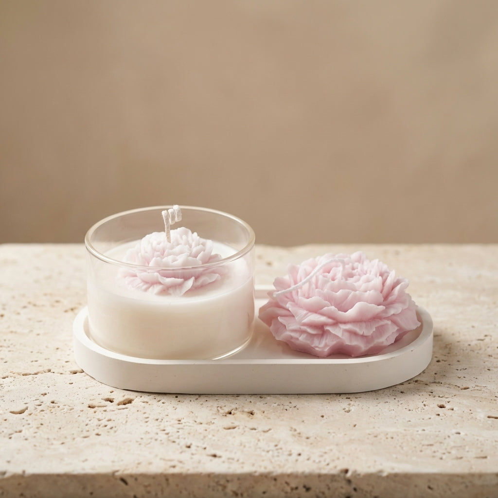 Close-up of the Blushing Peony Home Decor Trio featuring a pink sculptural peony candle and matching glass candle resting on a handcrafted oval gypsum tray.