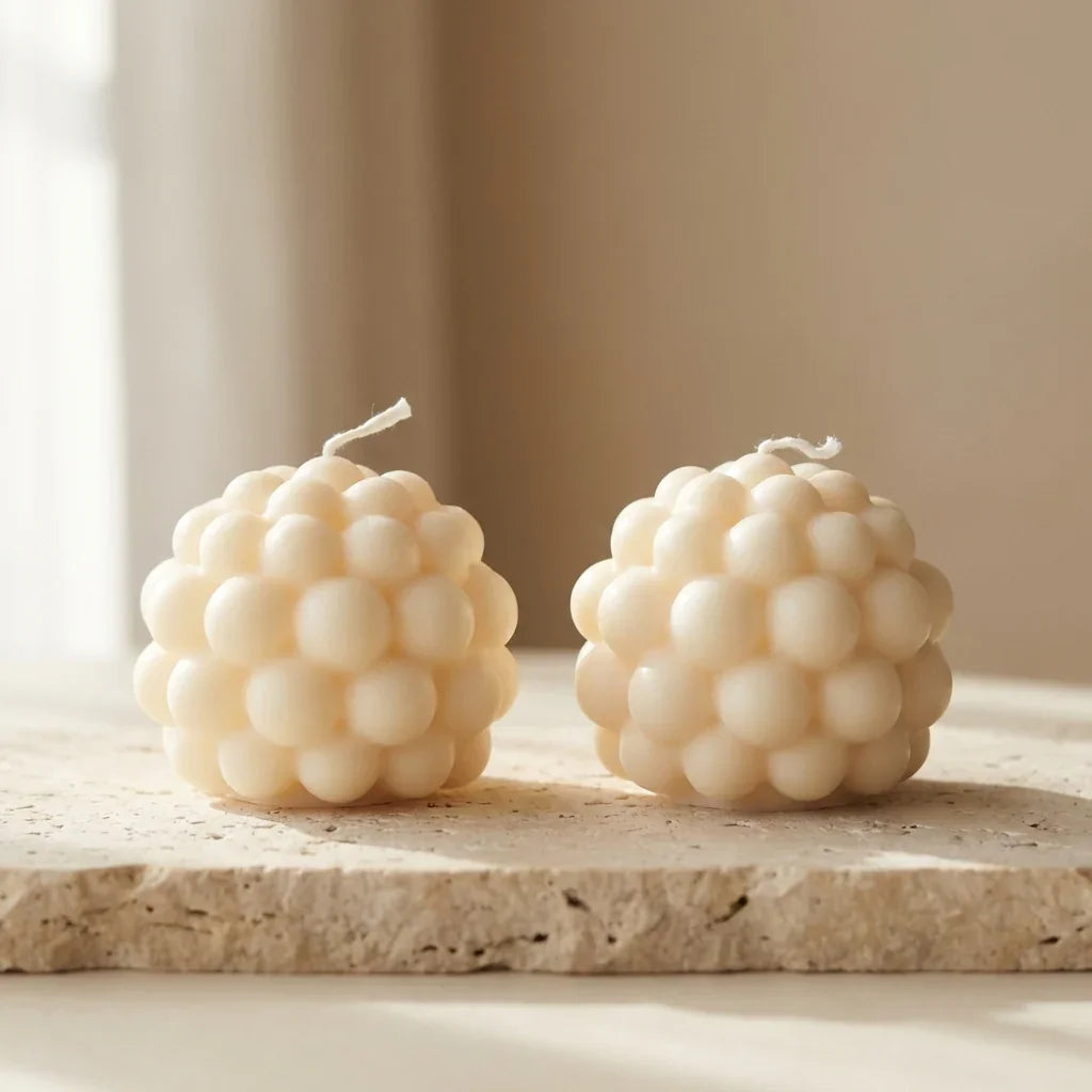 Two bubble-shaped candles on a stone surface with a neutral background