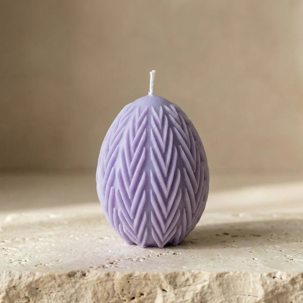 Close-up of a hand-poured soy wax egg candle highlighting its deeply embossed chevron leaf botanical pattern.