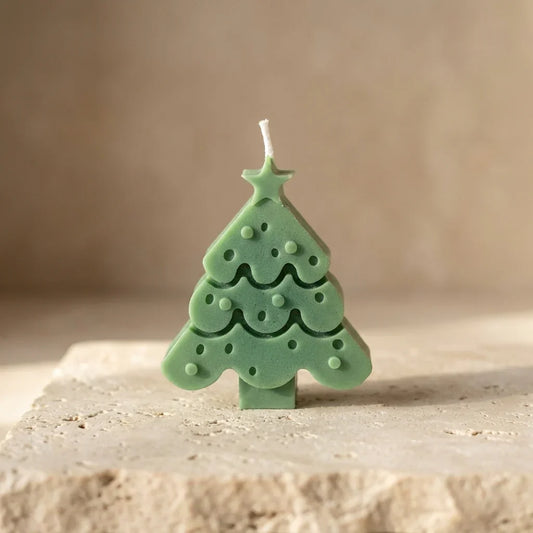 Green Christmas tree-shaped candle on a beige surface with a neutral background