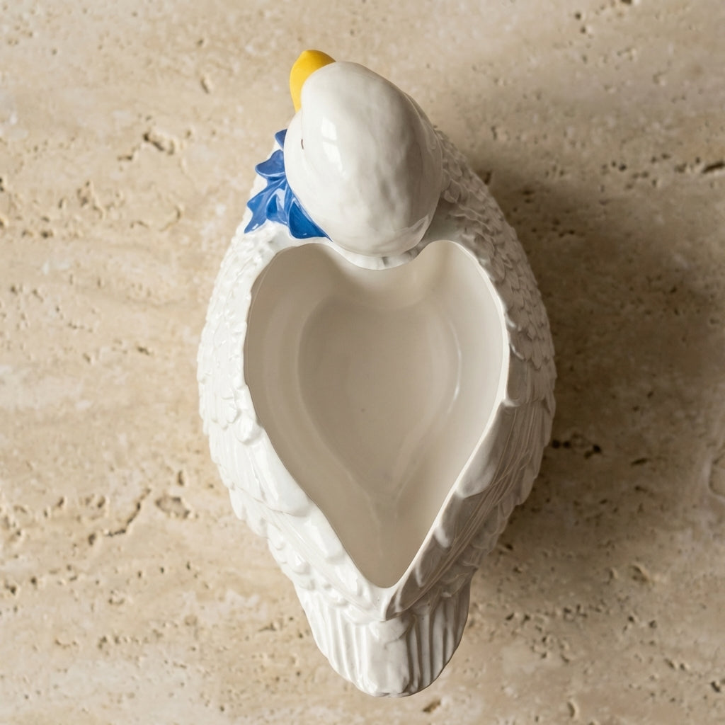 White ceramic duck-shaped bowl on a beige stone surface
