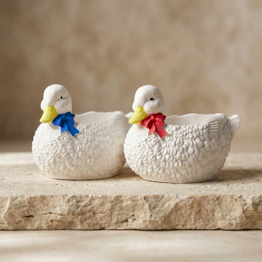 Close-up of a handcrafted gypsum duck vessel featuring a hand-painted yellow beak and red ribbon bow, with natural soy wax poured into a hidden heart-shaped cavity.