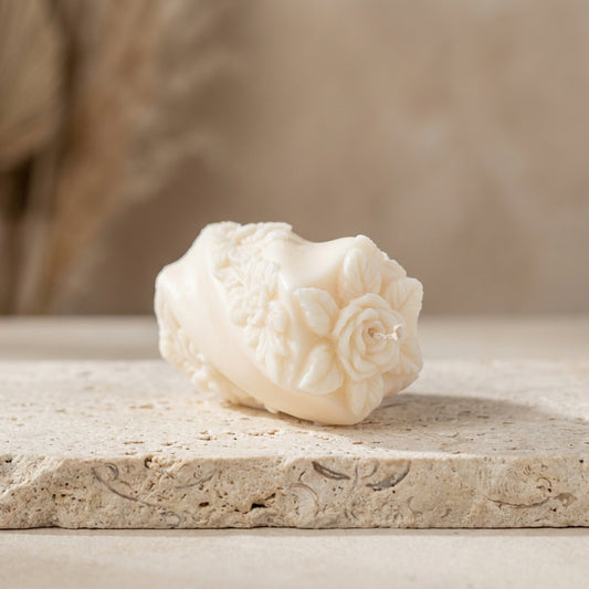 Embossed rose swirl candle styled beautifully as a romantic, vintage-inspired botanical accent on a bedroom nightstand.
