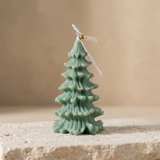 Green Christmas tree-shaped candle on a beige surface with a beige background