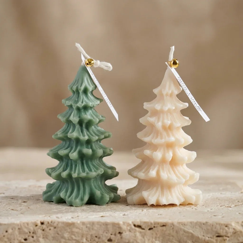 Two Christmas tree-shaped candles, one green and one beige, on a wooden surface with a neutral background.