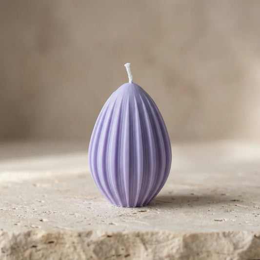 Close-up of a hand-poured soy wax fluted egg candle highlighting its clean, ribbed geometric lines and teardrop silhouette.