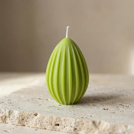 Close-up of a hand-poured soy wax fluted egg candle highlighting its clean, ribbed geometric lines and teardrop silhouette.