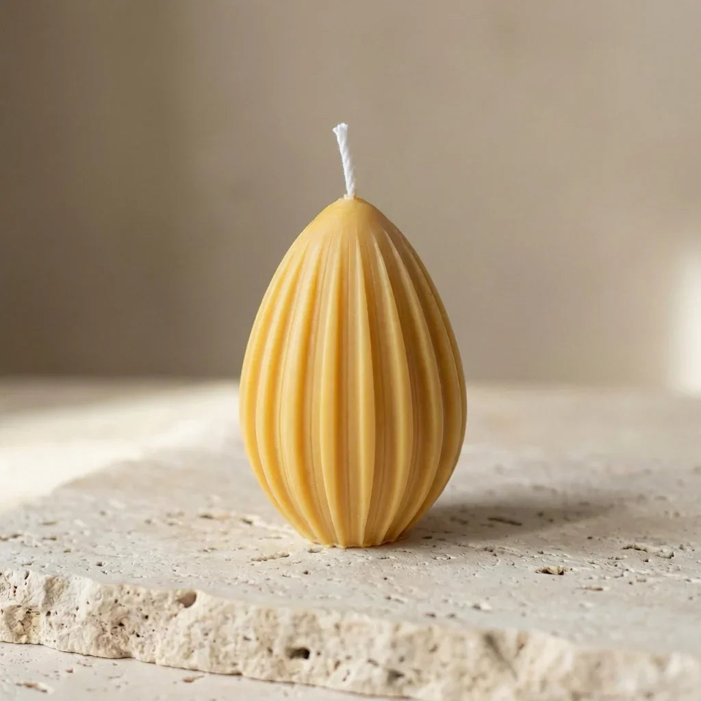 Close-up of a hand-poured soy wax fluted egg candle highlighting its clean, ribbed geometric lines and teardrop silhouette.