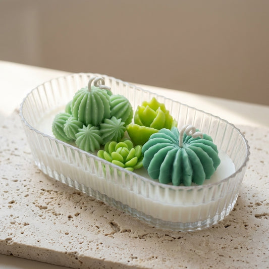 Close-up of a ribbed organic glass oval vessel featuring intricately detailed, hand-crafted wax cacti and succulents resting on top of natural white soy wax.