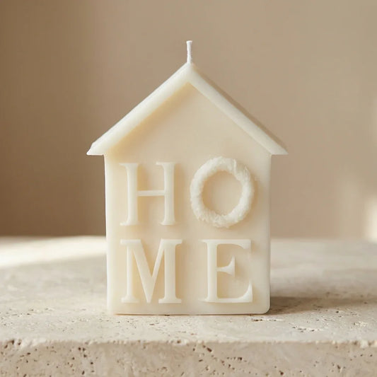 House-shaped candle with 'HOME' text on a neutral background