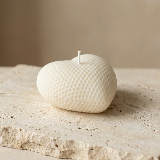 Close-up of a hand-poured soy wax honeycomb heart candle highlighting its plump, rounded silhouette and unique dimpled pattern.