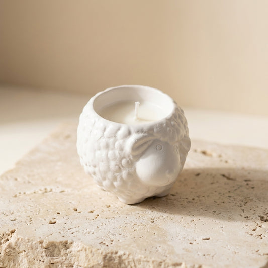Little lamb candle styled beautifully as a sweet, farmhouse-inspired decor piece on a wooden shelf in a cozy baby nursery.