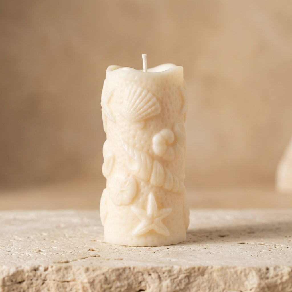 Close-up of a hand-poured soy wax ocean shell pillar candle highlighting intricately embossed seashells, starfish, and coastal textures.