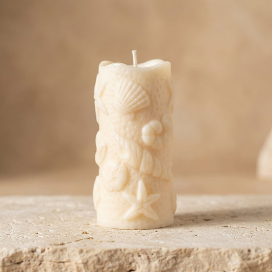Close-up of a hand-poured soy wax ocean shell pillar candle highlighting intricately embossed seashells, starfish, and coastal textures.