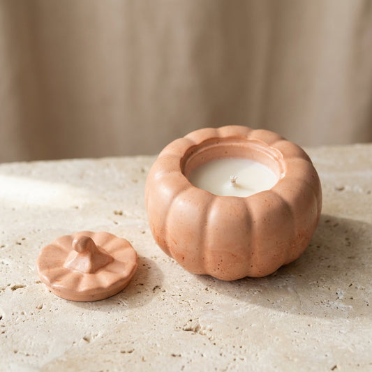 Close-up of a handcrafted terracotta-peach gypsum pumpkin vessel with a matching sculpted lid, featuring hand-poured natural soy wax inside.