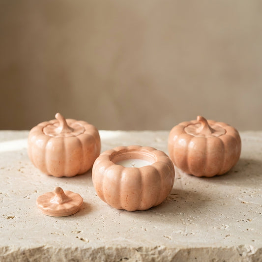 Pastel pumpkin candle with lid resting nearby, styled beautifully as cozy autumn decor on a warm, aesthetic coffee table setting.