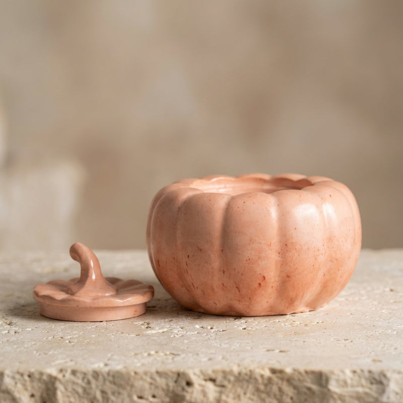 Close-up of a handcrafted pastel pumpkin jar highlighting its smooth, speckled terracotta-peach finish and matching sculpted lid.