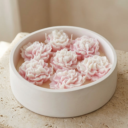 Close-up of a large, handcrafted matte gypsum bowl featuring seven wicks and a lush arrangement of intricately detailed pink and white wax peonies resting on top of natural soy wax.