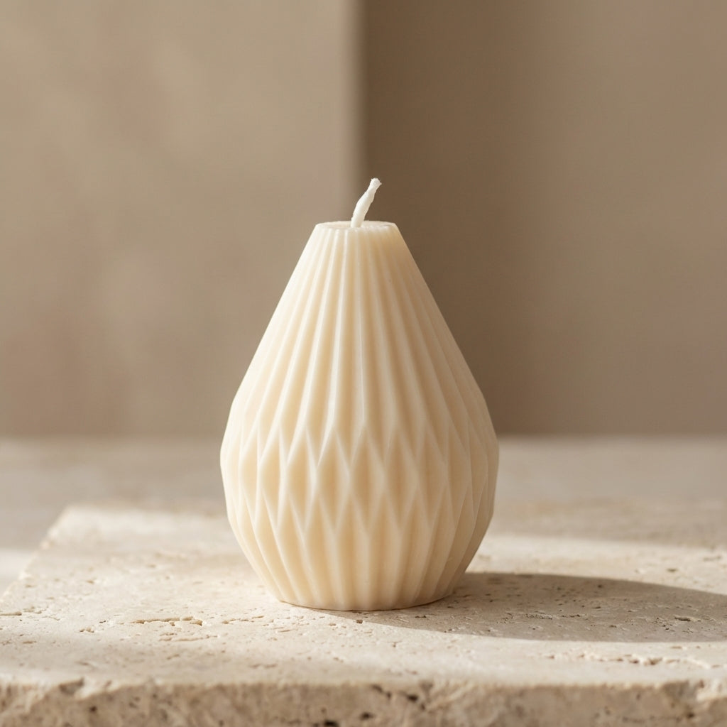 Petite faceted teardrop candle styled elegantly as a modern architectural accent on a minimalist coffee table.