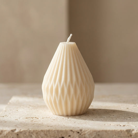 Petite faceted teardrop candle styled elegantly as a modern architectural accent on a minimalist coffee table.