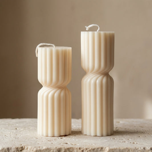 Close-up of a hand-poured soy wax ribbed hourglass pillar duo highlighting their classic fluted texture and contrasting heights.