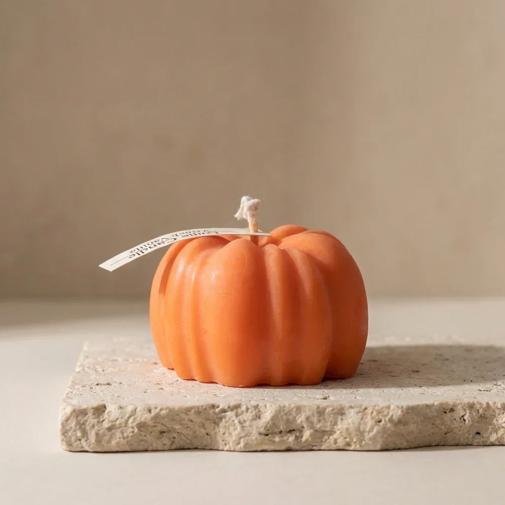Pumpkin-shaped candle on a stone surface with a neutral background