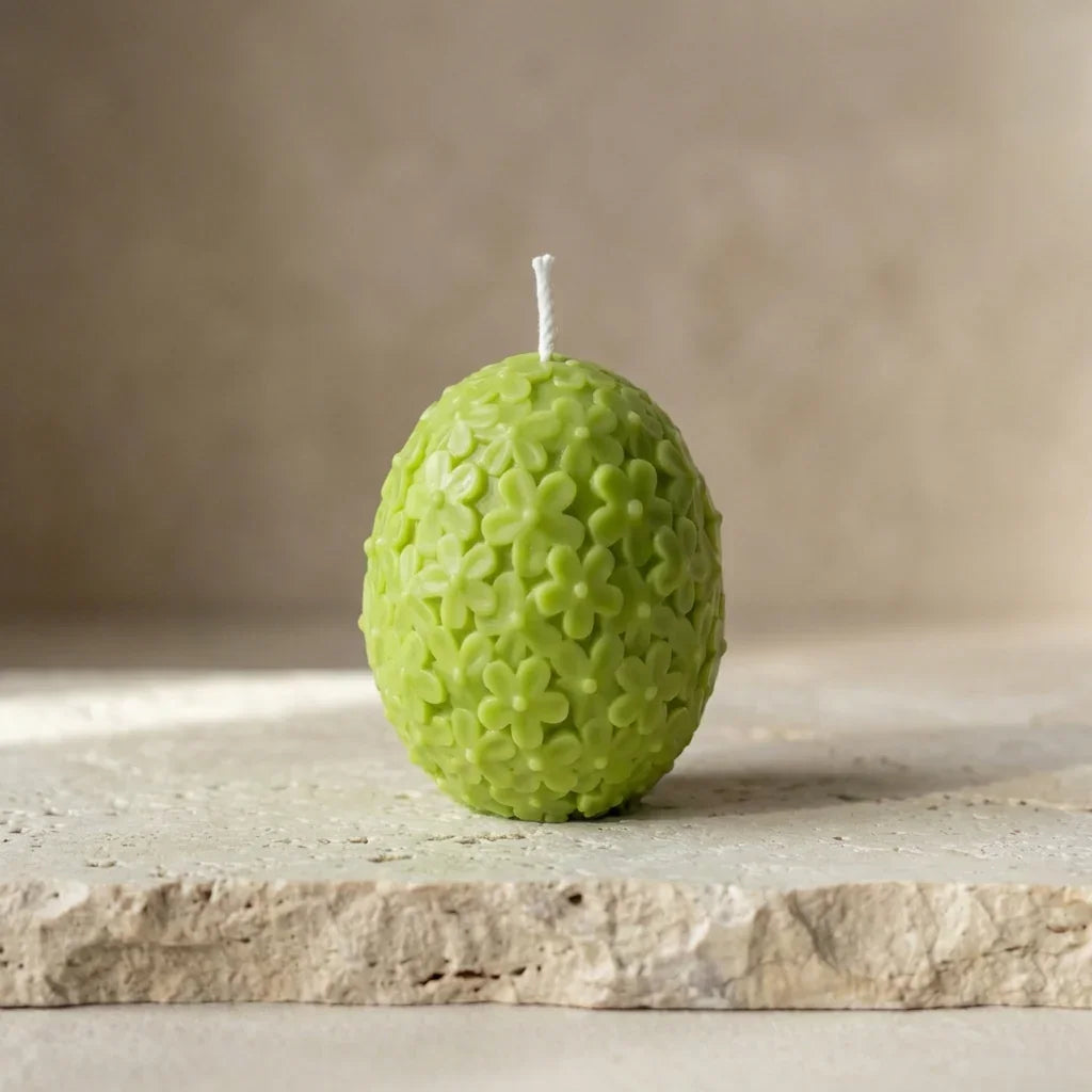 Close-up of a hand-poured soy wax floral egg candle highlighting its intricate, embossed daisy botanical pattern.