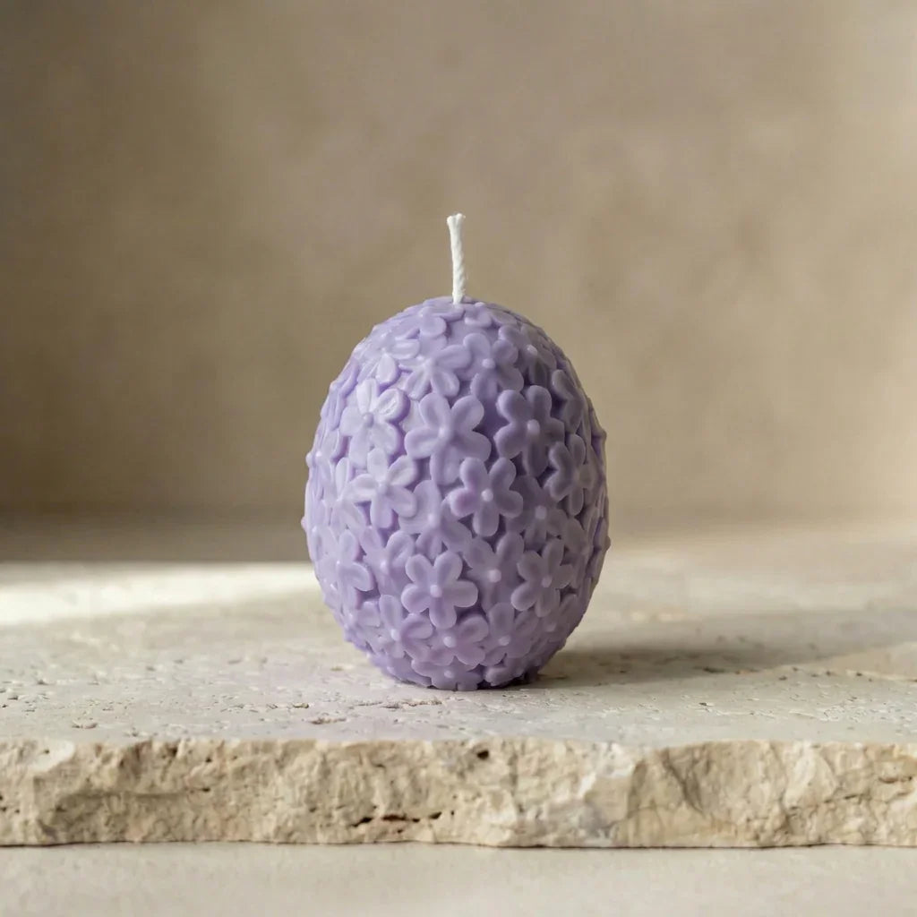 Close-up of a hand-poured soy wax floral egg candle highlighting its intricate, embossed daisy botanical pattern.