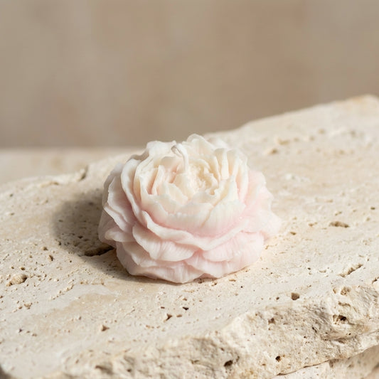 Close-up of a hand-poured soy wax sculptural peony blossom candle highlighting its soft blush hue and delicate, layered floral petals.