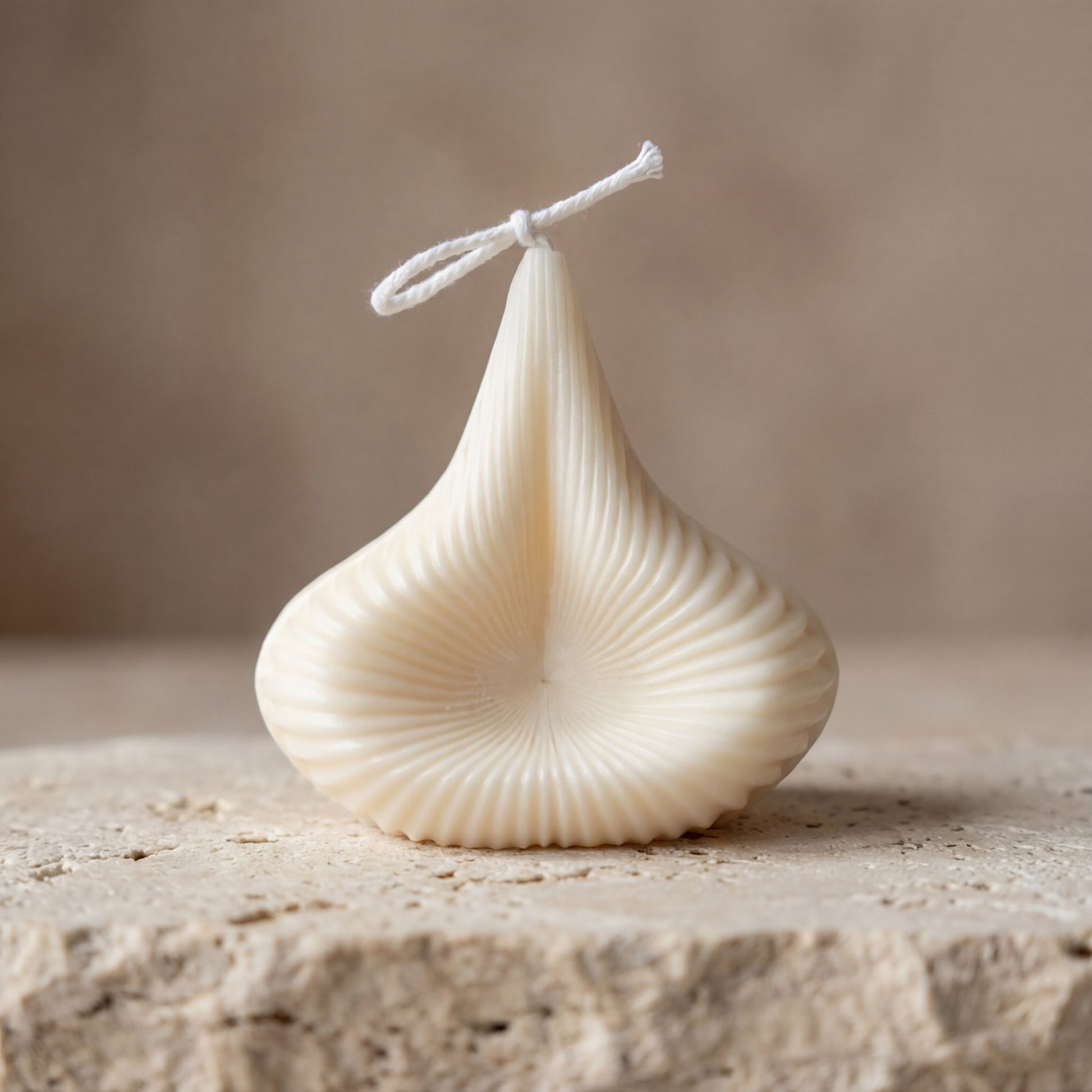 Close-up of a hand-poured soy wax sculptural swirl drop candle highlighting its abstract, deeply fluted seashell silhouette.