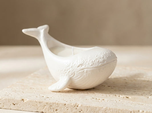 Close-up of a hand-poured white soy wax whale candle showing detailed barnacle textures and a 100% organic cotton wick.