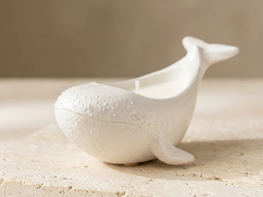 An adorable sculptural whale candle styled on a bathroom shelf as a nautical decorative accent.