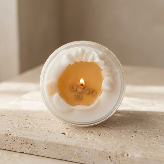A Secret Message Candle burning on a bedside table, revealing the words "LOVE U" in the golden melted wax pool.