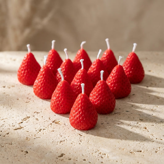 Close-up of a hand-poured soy wax strawberry cake candle highlighting its hyper-realistic red finish and delicate seed detailing.