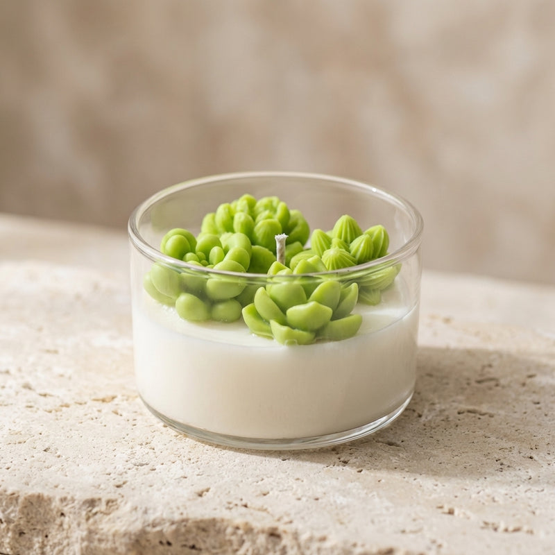 Close-up of a clear glass soy candle featuring highly detailed 3D green wax succulents and cacti resting on natural white soy wax.
