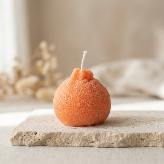 Close-up of a hand-poured soy wax tangerine candle highlighting its incredibly realistic, textured peel design.