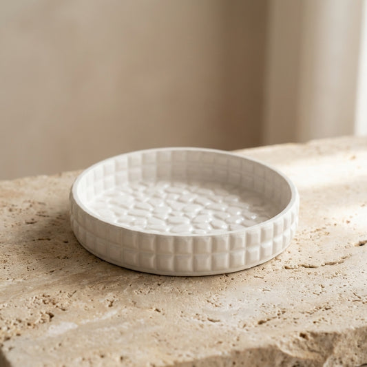 Close-up of a handcrafted textured gypsum tray highlighting its 3D cobblestone-patterned base and modern geometric grid rim.