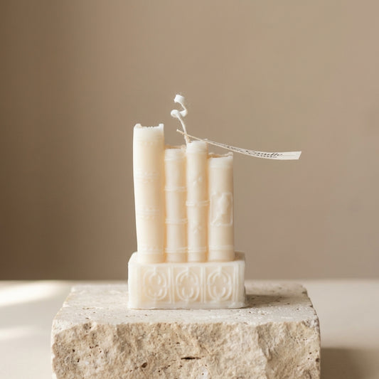 Close-up of a hand-poured soy wax vintage book stack candle highlighting its detailed, textured antique spines and embossed covers.