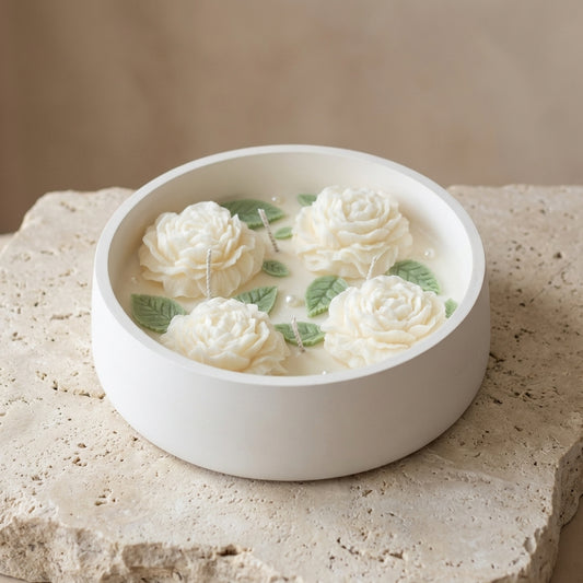 Close-up of a large handcrafted matte white gypsum bowl featuring four wicks and detailed white wax peonies with pearl accents on natural soy wax.