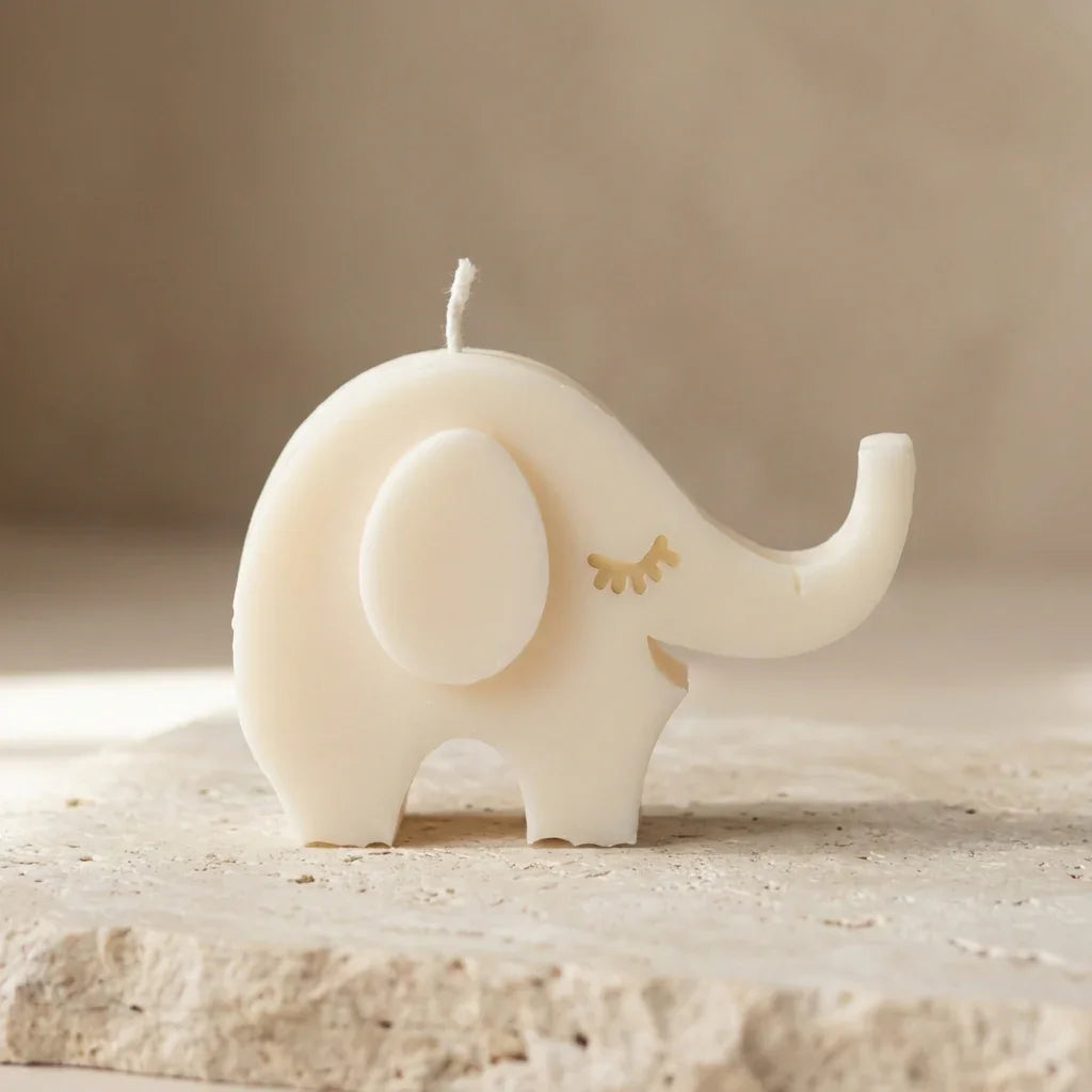 Candle shaped like an elephant on a stone surface with a neutral background
